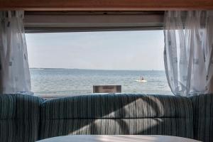 una ventana con sofá y vistas al océano en Przyczepa w pierwszej linii brzegowej - Kemping Molo Surf, en Jastarnia
