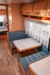 uma pequena cozinha com um sofá e uma cama num quarto em Przyczepa w pierwszej linii brzegowej - Kemping Molo Surf em Jastarnia