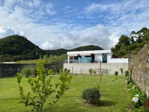 a house in a field with a stone wall at CaLoura 76 in Lagoa