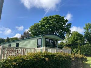 a green tiny house with a porch at 2 bedroom chalet in Chwilog on the Llyn Peninsula in Pwllheli