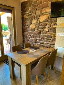 una mesa de madera con sillas frente a una pared de piedra en Casamia4u, en Alsóörs