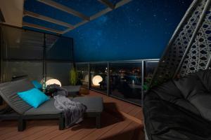 a balcony with a chair and a table on a deck at night at Lighthouse Luxury Penthouse - Jantar Apartamenty in Mrzeżyno