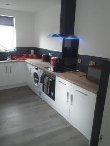 a kitchen with a stove and a washing machine at J & S Apartments in Ayr