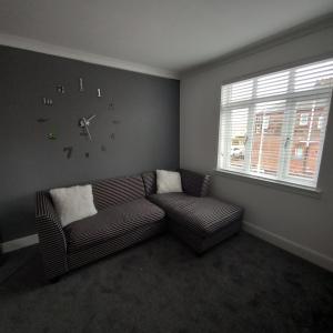 a living room with a couch and a clock on the wall at J & S Apartments in Ayr