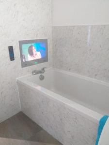 a bathroom with a bath tub with a tv on the wall at J & S Apartments in Ayr