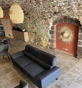 uma sala de estar com um sofá e uma parede de pedra em Gite "La Coline d'Océane" - Neffies em Néffiès