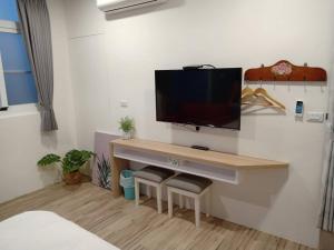 a room with a desk with a television on a wall at The Railroad Runs in Taitung City