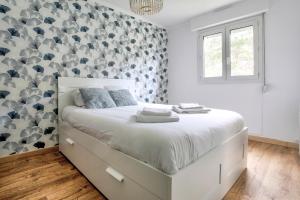 a bedroom with a large bed with a wall covered in gray and white at Les Ebihens - Studio et chambre indépendante in Saint-Cast-le-Guildo