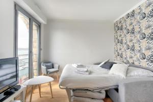 a living room with a bed and a tv at Les Ebihens - Studio et chambre indépendante in Saint-Cast-le-Guildo