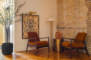2 Stühle und eine Lampe in einem Zimmer mit Ziegelwand in der Unterkunft Found Chicago powered by Sonder in Chicago