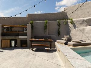 a patio with a table and a bench next to a pool at Nomad Mykonos - Small Luxury Hotels of the World in Kalo Livadi