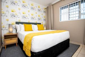 a bedroom with a large bed with yellow pillows and a window at Unit 416 at Menlyn Place in Pretoria