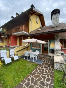 a house with a patio with chairs and an umbrella at Vacanza da sogno nell’Altopiano. in Gallio