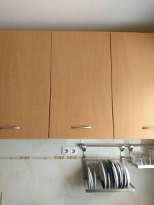 a kitchen with wooden cabinets and plates on a shelf at Apartamento acolhedor na Cidade da Praia in Praia