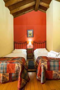 twee bedden in een kamer met rode muren bij Ca PilaronaLa CuadraMallecina in Salas