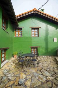 una casa verde con una mesa y sillas frente a ella en Ca PilaronaLa CuadraMallecina, en Salas