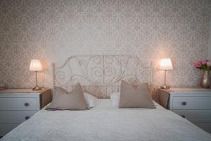 sypialnia z białym łóżkiem z 2 lampami i kwiatami w obiekcie Vacation House Vila Mia w Bledzie