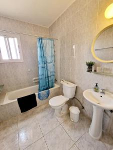 een badkamer met een toilet, een wastafel en een bad bij Emma's Place, 2 bedroom apartment with pool view in Paphos City