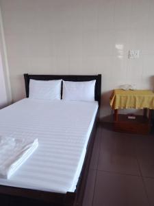um quarto com uma cama branca e uma mesa amarela em Nhà nghỉ Hằng Nga em Dong Hoi