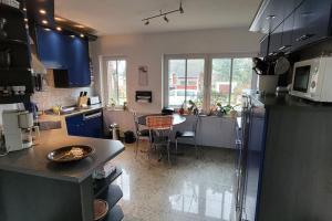 eine Küche mit blauen Schränken und einem Tisch darin in der Unterkunft Behagliches Haus am Waldrand in Nähe von Berlin 
