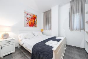 a white bedroom with a bed and a painting on the wall at Tramonto in Zadar