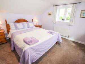 1 dormitorio con 1 cama grande con mantas moradas en Lavender Cottage, Brailes, en Lower Brailes