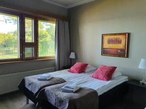 a bedroom with a large bed with two pink pillows at Hotelli Viikinhovi in Keuruu