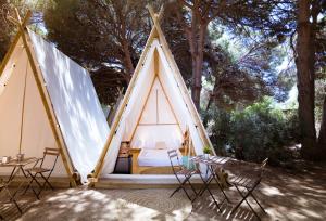 Tienda de campaña con cama y sillas en un patio en Kampaoh Picos de Urbión, en Abejar