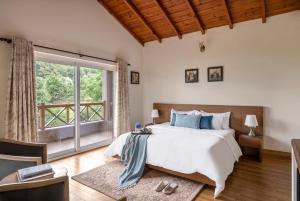 a bedroom with a bed and a large window at SaffronStays Plaksha, Mukteshwar in Mukteswar