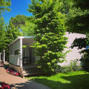 una casa con un porche y un árbol en Luxury Camp at Union Lido, en Cavallino-Treporti