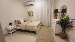 a white bedroom with a bed and a mirror at شقة كبيرة عائلية VIP حي الوادي in Riyadh