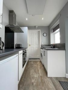 a kitchen with white cabinets and a white door at Cosy & Comfortable Apartment w/Parking in Worksop