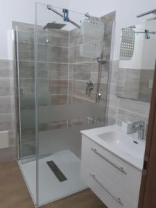 y baño con ducha acristalada y lavamanos. en Affittacamere da Claudio&Kevin con uso cucina, en Posada