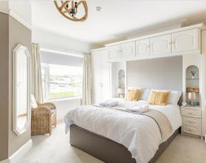 a white bedroom with a large bed and a window at Larkhill House in Portrush
