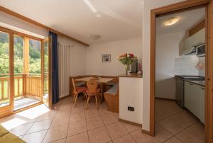 a kitchen and dining room with a table and a balcony at Residence Kristall- Fiemme Holidays in Predazzo