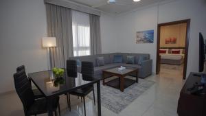 Anisa Residential Complex في صلالة: غرفة معيشة مع أريكة وطاولة مع كراسي