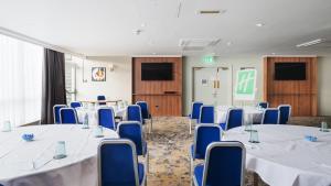 ダービーにあるHoliday Inn Derby/Nottingham, an IHG Hotelの白いテーブルと青い椅子が備わる会議室