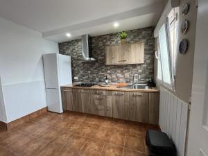 eine Küche mit Holzschränken und einem weißen Kühlschrank in der Unterkunft MIRADOR SAN ROQUE in Las Palmas de Gran Canaria