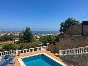 una piscina con una valla y sillas y el océano en Villa Seaview Suncoast Luxury, en Málaga