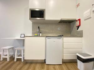 a kitchen with white cabinets and a white refrigerator at Canto Doce in Setúbal