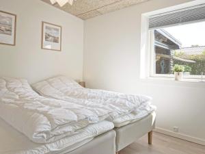 białe łóżko w pokoju z oknem w obiekcie Holiday home Rønne VI w mieście Rønne