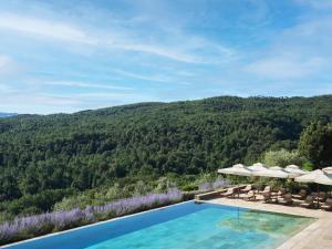 uma piscina com guarda-sóis e uma montanha em Rosewood Castiglion del Bosco em Castiglione del Bosco