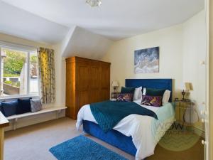 um quarto com uma cama azul e uma janela em Haslemere - Beer Devon em Beer