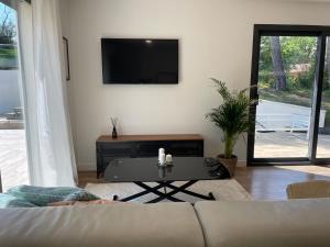 un soggiorno con divano, tavolo e TV di Villa-jacuzzi-1chb-jardin-10minsAixEnPce-QuartierChic a Meyrargues