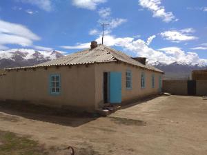 uma pequena casa com montanhas ao fundo em Song-Kul Kyzart, GH Alia em Kyzart