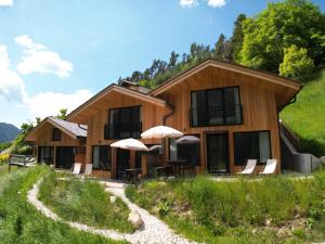 a house on a hill with chairs and umbrellas at Chalet Tschogerhof Tiers am Rosengarten Dolomiten in Tires