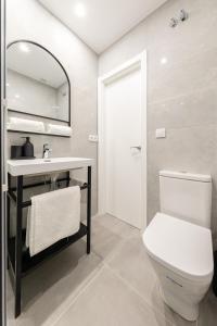 a bathroom with a toilet and a sink and a mirror at Indulge en Sevilla Cuna in Seville