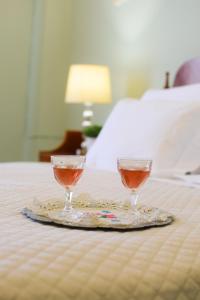 dois copos de vinho numa bandeja numa cama em Margaret's house em Corinto