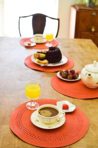 uma mesa com pratos de comida e um copo de sumo de laranja em Margaret's house em Corinto