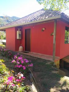 una casa roja con flores delante en Chalé Sorrizão- Visconde de Mauá, en Bocaina de Minas